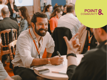 Man with beard sitting on a table engaging with other people